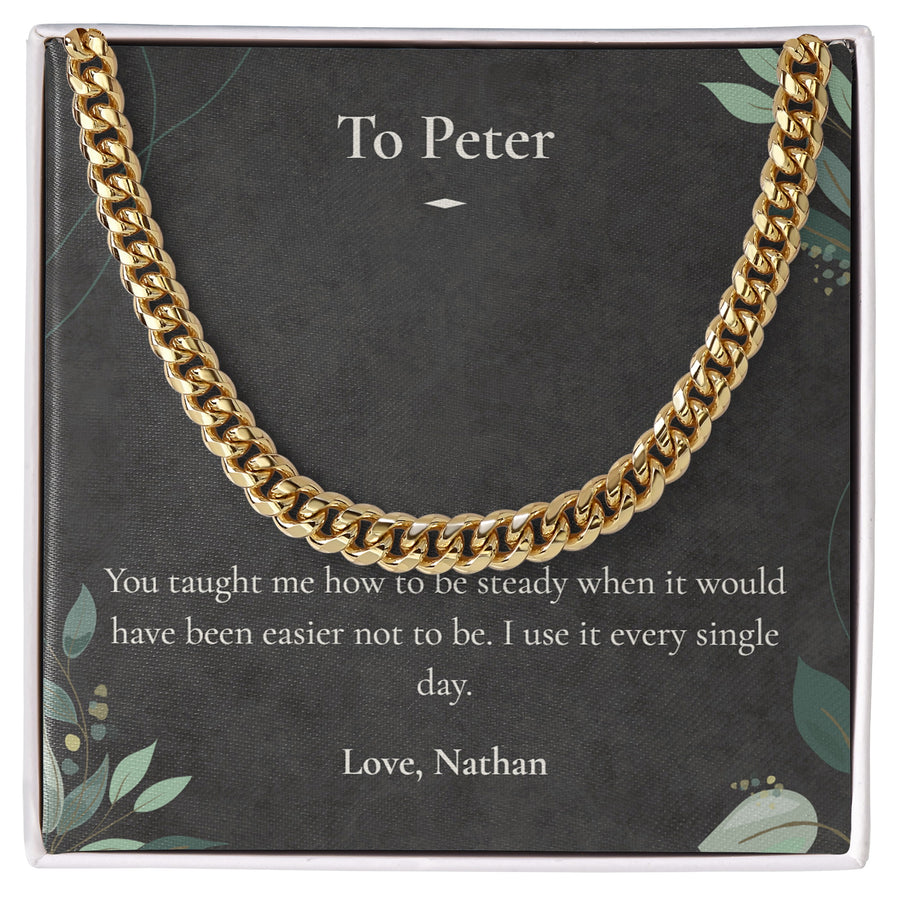 Gold Cuban Link Chain lying on a personalised message card addressed to Peter.